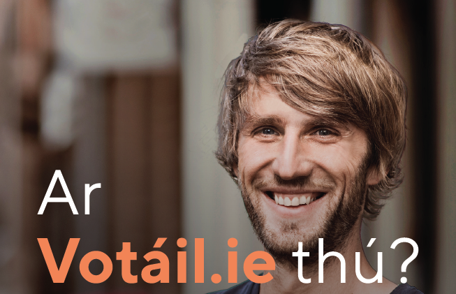 Aghaidh doiléir duine le gruaig dhonn éadrom sa lár. Tá an cúlra doiléir freisin. Tá téacs Gaeilge le feiceáil ar an íomhá: “Ar Votáil.ie thú?”, le “Votáil.ie” i ndath oráiste agus an chuid eile i bán.
