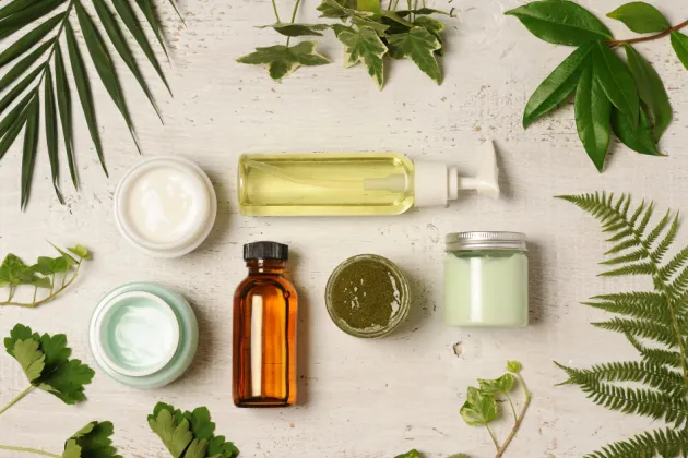 Image of skin care bottles in a flat lay display surrounded by leaves
