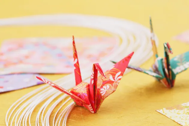 Image of a red origami bird on a yellow table