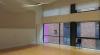 a large room with wooden floors, floor to ceiling windows and a projection screen