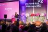 jess kelly stands on stage presenting a panel talk