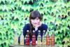 woman leans on table covered in bottles of kombucha.