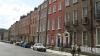 a street with cars parked and two people stopped to talk