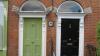 Front face of two buildings with a green and black door