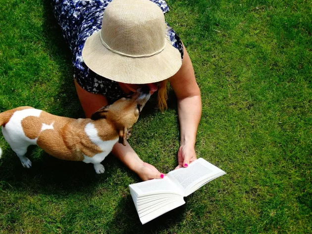 Woman reading on the lawn with dog