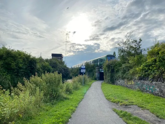 Image of a foot path leading to a short tunnel below a train track