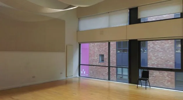 a large room with wooden floors, floor to ceiling windows and a projection screen