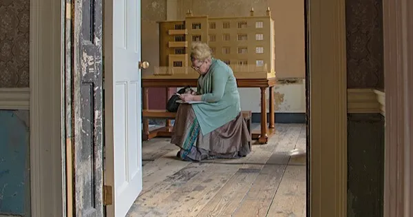 a woman leans forward drawing in an old georgian room