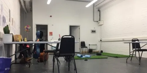 a white room with chairs, tables, mats and musical instruments