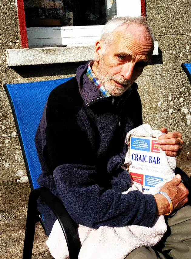 Man holding book sitting in a garden