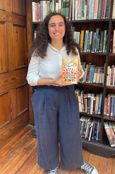 A member of staff holding the Agatha Christie Novel Death Comes as The End