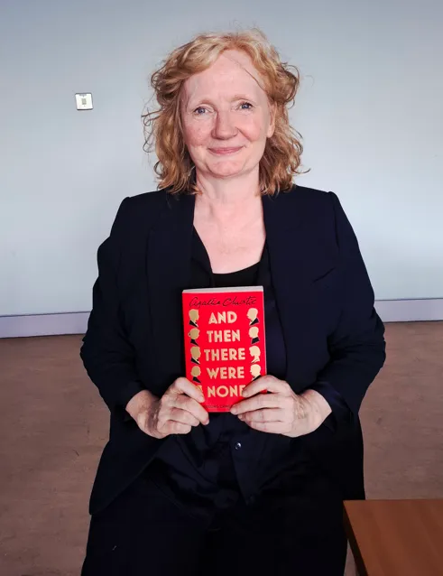 A member of staff holding the Agatha Christie novel And Then There Were None