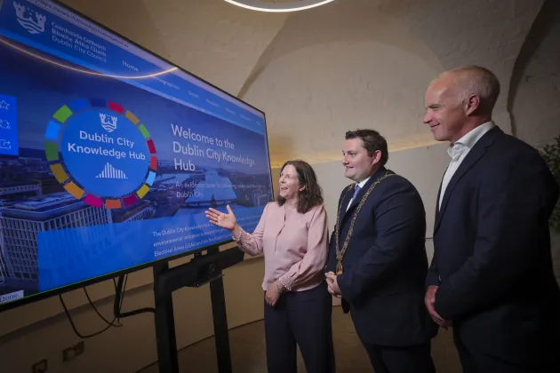 Three people look at a screen which says 'Welcome to Dublin City Knowledge Hub'