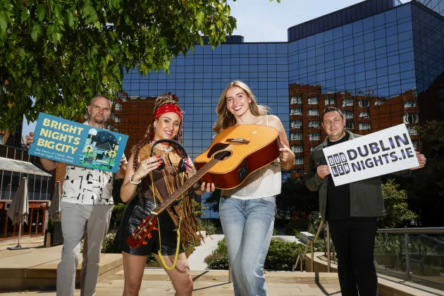 4 people holding signs that say bright nights big city and dublin.ie