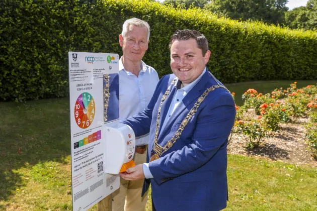 Photo of two men standing in a garden smiling 