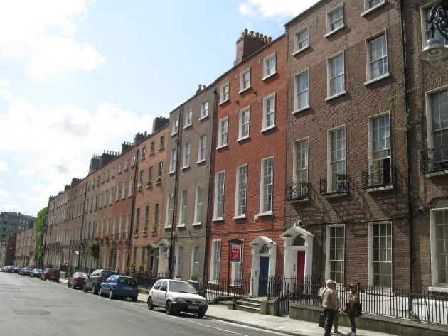 a street with cars parked and two people stopped to talk