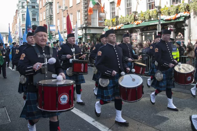 Pipe band marching down the street with cheering crowds