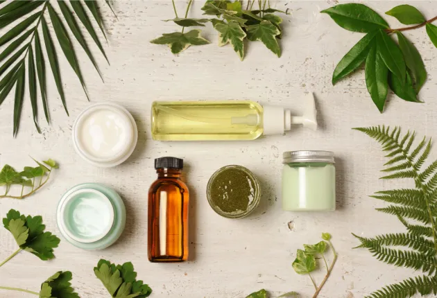 Image of skin care bottles in a flat lay display surrounded by leaves