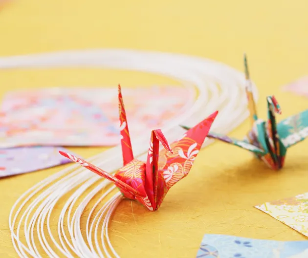 Image of a red origami bird on a yellow table