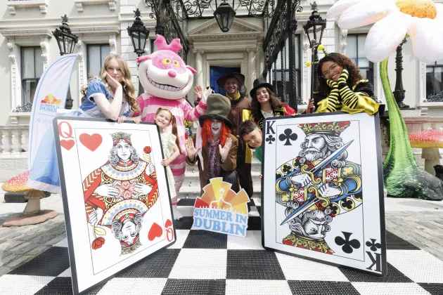 People dressed as Alice in Wonderland characters pose with large playing cards