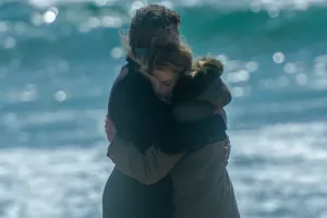 man and women hugging in front of a blue sea